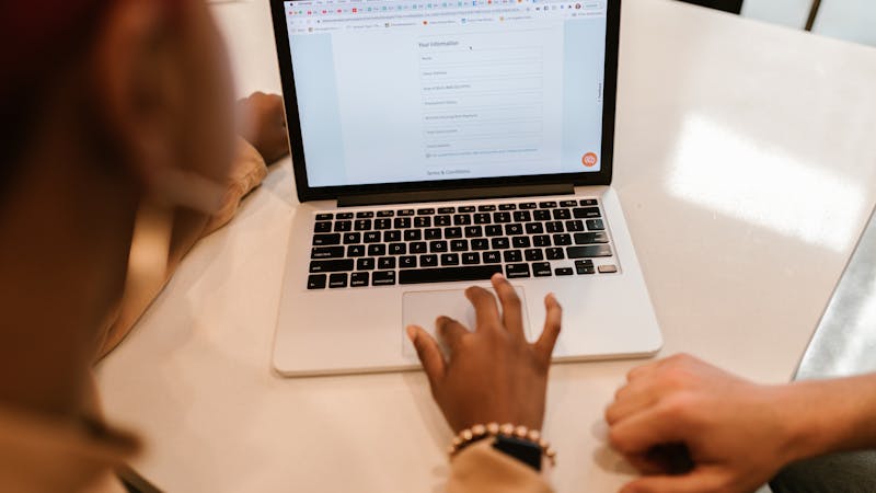 Person typing input into a form field on a laptop keyboard