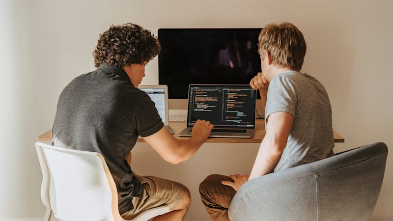 Two developers pair programming together at a shared workstation